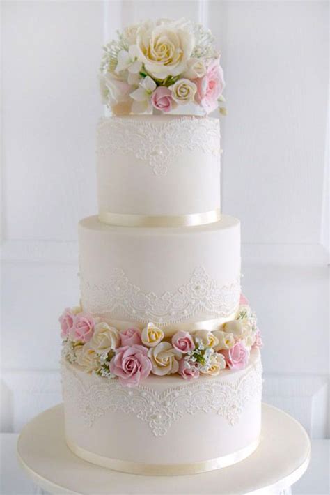 A Three Tiered White Wedding Cake With Pink And White Flowers