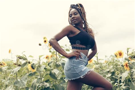 African American Girl In A Field Of Yellow Flowers At Sunset Stock