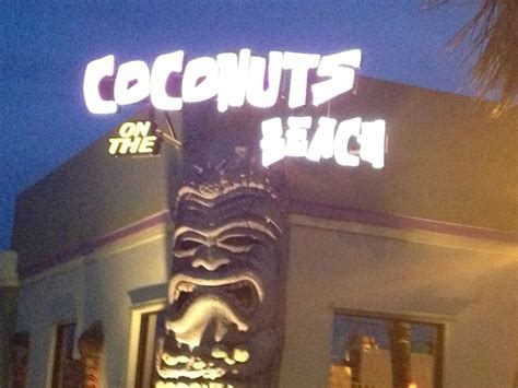 a sign that says coconuts on the beach in front of a building at night