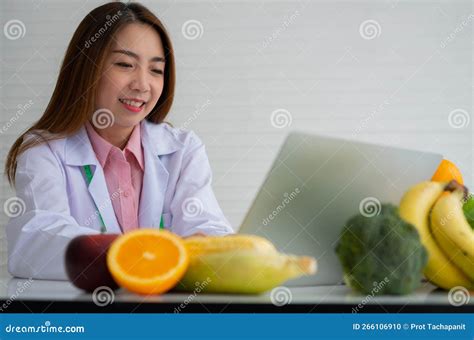 Portrait Of Asian Smiling Female Nutritionist Typing On Laptop Computer