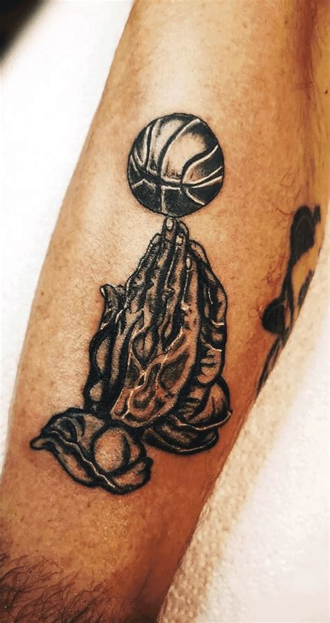 A Man With A Tattoo On His Arm Holding A Basketball Ball And Praying To God