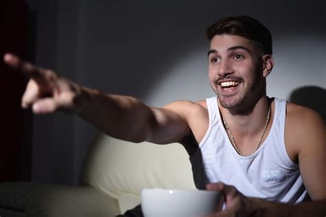 Premium Photo Young Man Eating Popcorn And Watching Movies