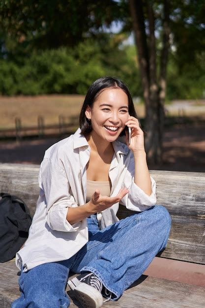 Retrato de uma jovem asiática feliz falando no celular no parque