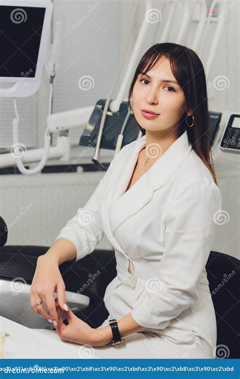 Portrait Of Attractive Smiling Female Dentist With Hands Folded Stock