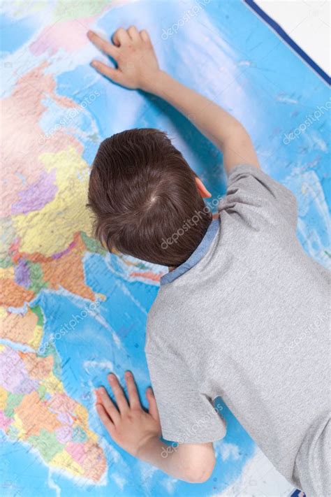 Niño serio estudiando mapa del mundo 2023