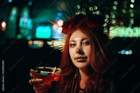 Female With Skeleton Makeup At A Halloween Party Holds Cocktail And