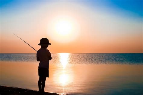 Um pescador infantil feliz pescando à beira mar em viagens de silhueta