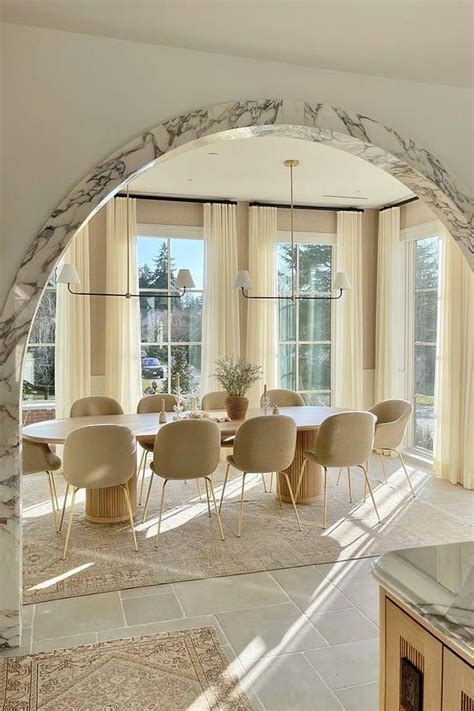 An Arch In The Middle Of A Dining Room With Chairs And A Marble Table