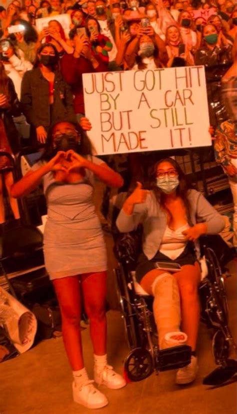 Two Women In Wheelchairs Hold Up Signs While Others Watch From The