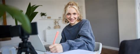 Portrait d une étudiante blonde souriante qui étudie à la maison en apprenant à écrire des notes