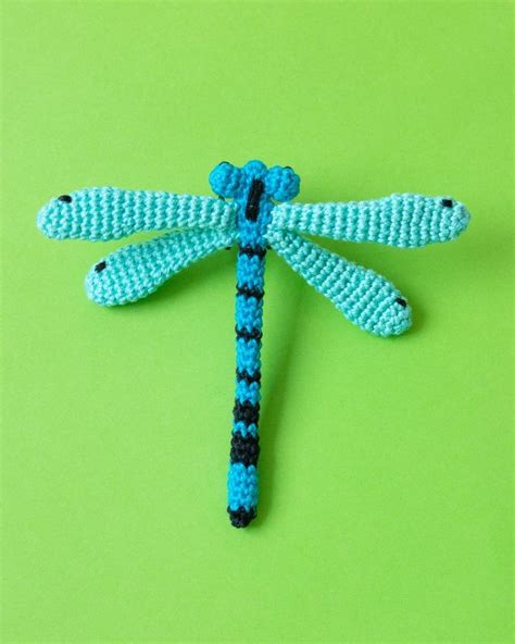 A Crocheted Dragonfly Sitting On Top Of A Green Surface