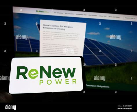 Person Holding Cellphone With Logo Of Indian Company Renew Energy