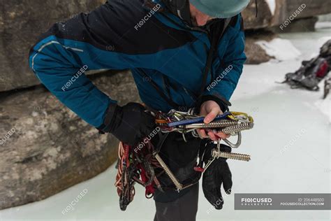 Homem alpinista vestindo arnês perto de montanha rochosa durante o