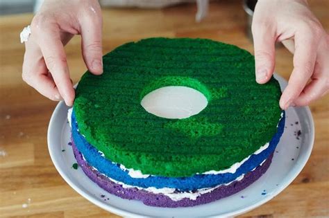 A Person Is Decorating A Cake With Green Frosting On A White Platter