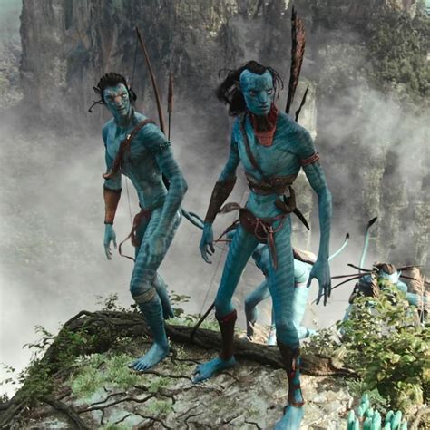 Two People Dressed In Blue Standing On Top Of A Mountain