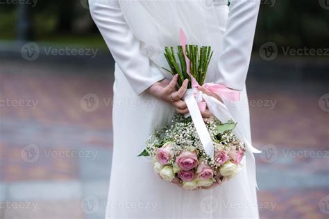 The bride in a white wedding dress is holding a bouquet of white ...