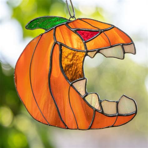 A Stained Glass Pumpkin Ornament Hanging From A Tree