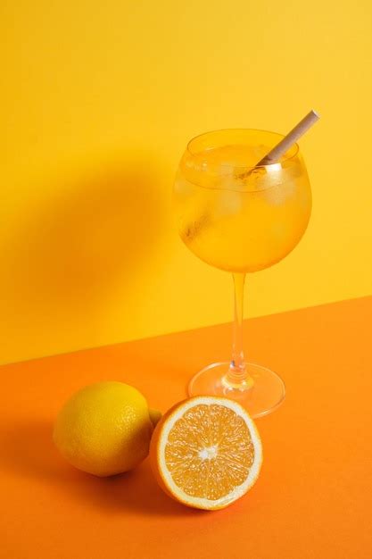 Premium Photo Cocktail Glass With Yellow Ice And A Straw Orange Lemon Background In Minimalist