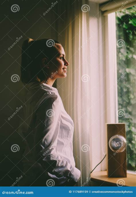 Woman Wearing White Long Sleeved Shirt Standing In Front Of The Window With White Curtain