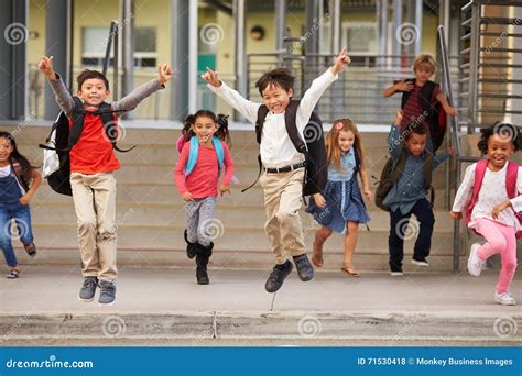 A Group Of Energetic Elementary School Kids Leaving School Stock Photo