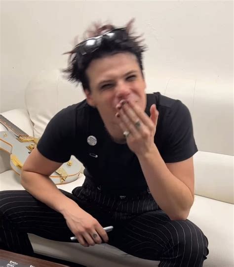 A Woman Sitting On Top Of A White Couch Holding Her Hands To Her Mouth