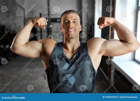 Jeune Homme Heureux Montrant Ses Muscles Biceps En Gym Image Stock