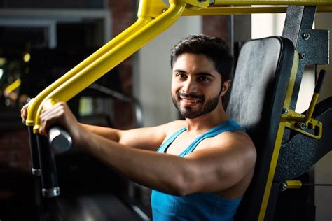 Homem bonito asiático indiano malhando ou se exercitando na academia