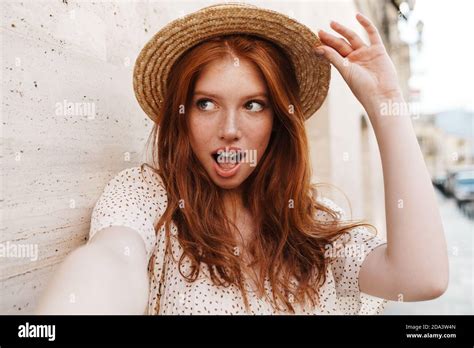 Image Of Seductive Ginger Girl In Straw Looking Aside While Taking Selfie At City Street Stock