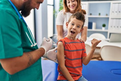 Young Kid Getting Vaccine At Doctor Clinic Pointing Thumb Up To The