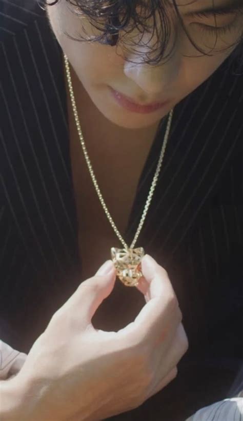 A Woman Wearing A Suit And Holding Onto A Necklace That Has A Flower On It