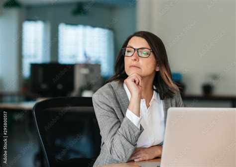 Businesswoman Thinking About Work While Sitting At Her Office Desk