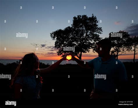 Hands forming heart around sunset Stock Photo - Alamy