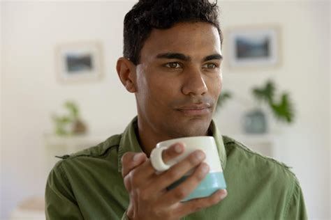 Premium Photo Thoughtful Biracial Man Holding Mug And Looking Away At