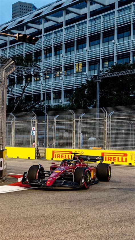 A Red And Yellow Race Car Driving On A Track In Front Of A Tall Building