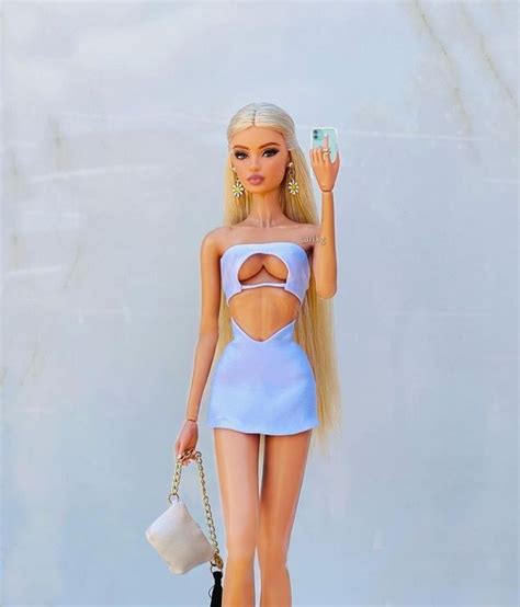 A Barbie Doll With Blonde Hair And Blue Dress Holding A Cell Phone In