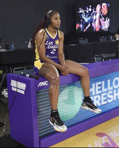 a woman sitting on top of a purple bench in front of a tv screen with ...