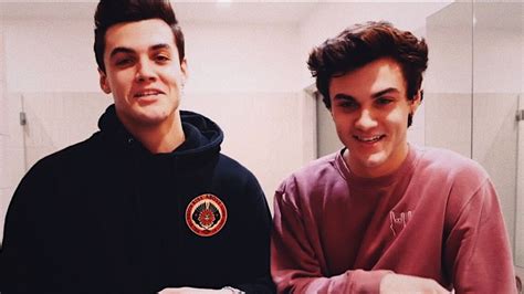 Two Young Men Sitting Next To Each Other In Front Of A Bathroom Mirror