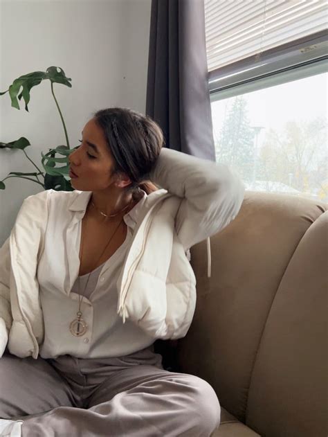 a woman sitting on top of a couch next to a plant