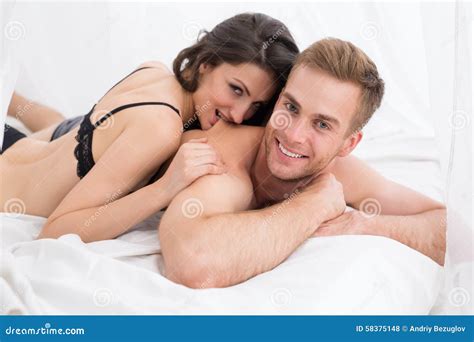 Jeunes Couples Heureux Se Situant Dans Le Lit Blanc Photo Stock Image