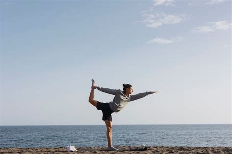 Hombre De Tiro Completo Haciendo Yoga En La Playa Foto Gratis