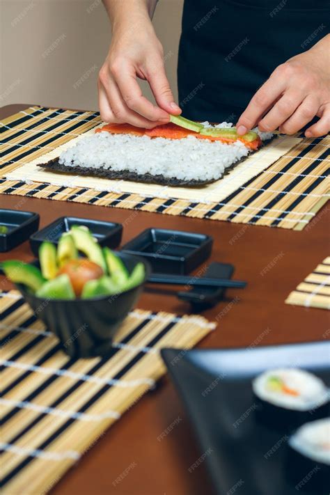 Premium Photo | Chef hands placing ingredients on rice to make sushi