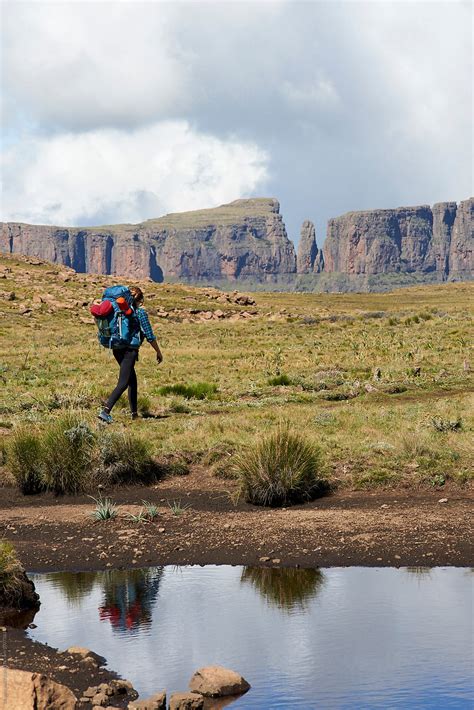 Female Hiker With Her Back Pack Hiking Through A Grass Field