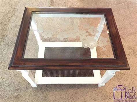 A Coffee Table With A Glass Top And Wooden Frame On Carpeted Floor Next