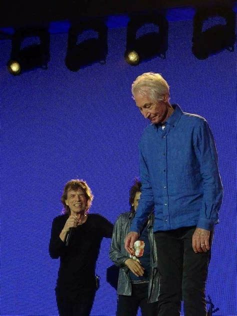 An Older Man Standing On Top Of A Stage Next To Two Other People In