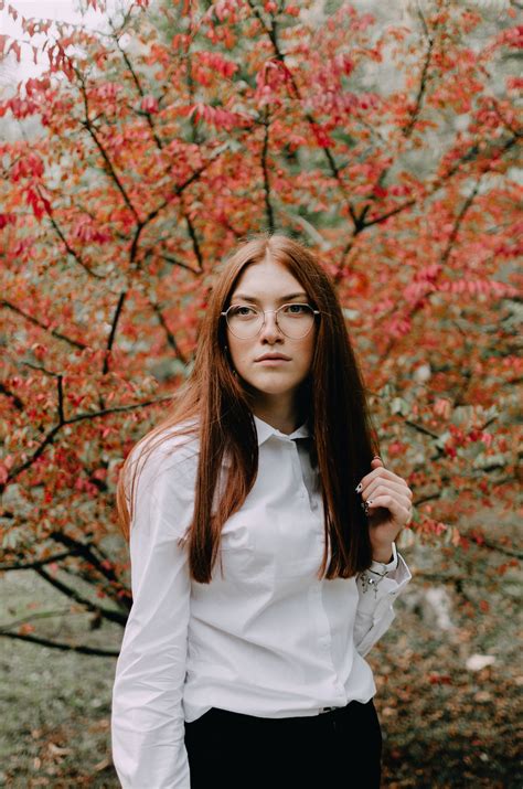 Woman In White Long Sleeve Shirt Standing Near Brown Leaves Tree During Daytime Photo Free