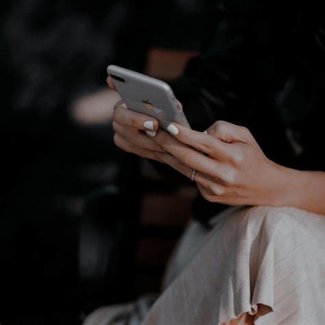 A Woman Sitting On A Bench Holding A Cell Phone In Her Hand And Looking