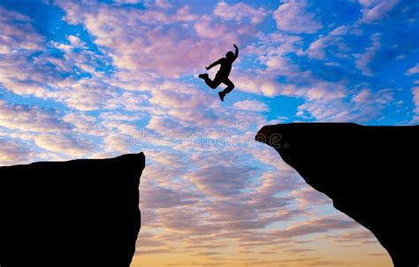 Silhouette Concept Idea A Man Jumping Over Cliff On Sunset Background