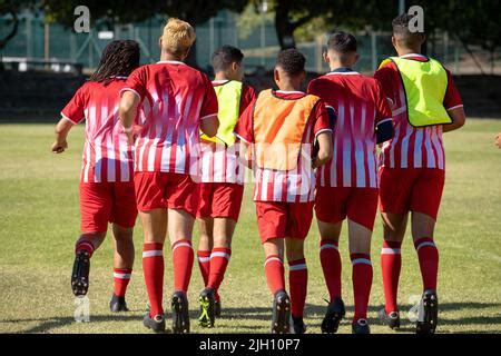 Multiracial Male Soccer Players Wearing Red Sports Uniforms Running On