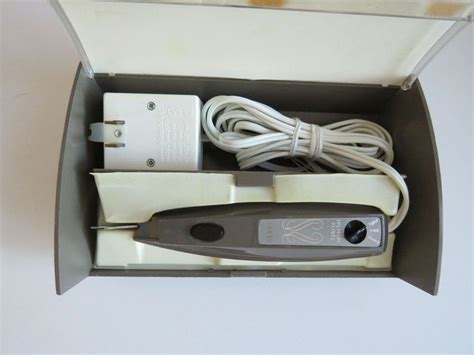 An Electronic Device In A Cardboard Box With Wires And Plugs Attached