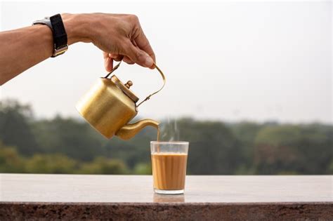 Hand Pouring Masala Tea From A Teapot Into A Glass Photo Premium Download